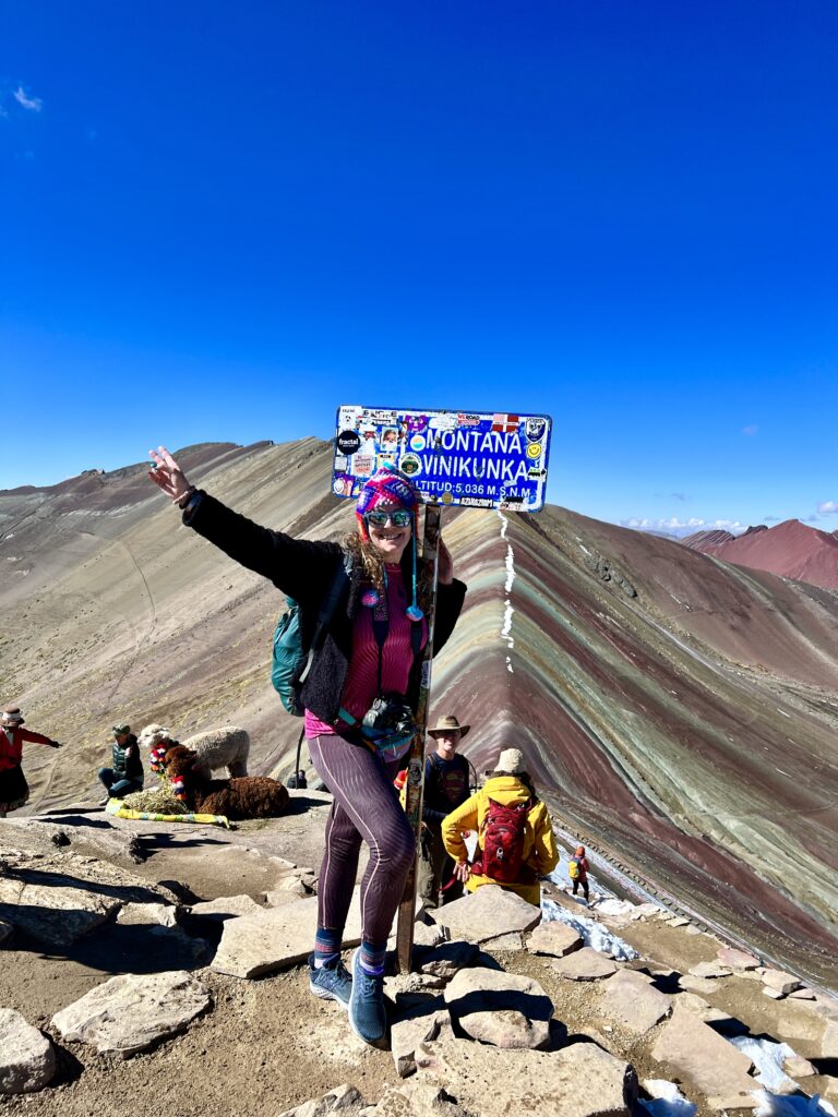 Woman standing at altitude marker for Mt. Vinikunka, Peru